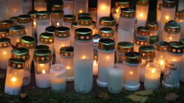 Sessiz bir mezarlıkta mumları yakmak, titreyen sıcak alevler mezar taşlarını yakmak ve 4K ultra HD ile yakalanan barışçıl bir anıt atmosferi yaratmak..