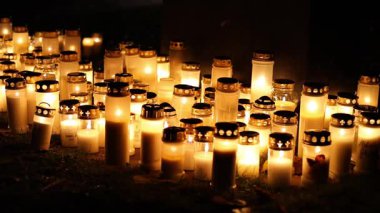 Sessiz bir mezarlıkta mumları yakmak, titreyen sıcak alevler mezar taşlarını yakmak ve 4K ultra HD ile yakalanan barışçıl bir anıt atmosferi yaratmak..