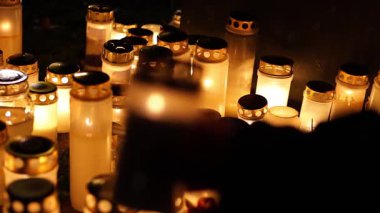 Sessiz bir mezarlıktaki mezara yanan bir mum koyan, mezar taşını aydınlatan yumuşak, ılık bir ışık ve 4K ultra HD 'de yakalanan bir anı ve yas anı yaratan kişi..