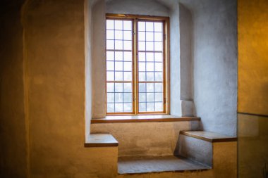 Antika mobilyalarla, taş duvarlarla ve sıcak ışıkla dolu eski bir şato. Tarih ve gizemle dolu bir ortaçağ atmosferi yaratıyor..