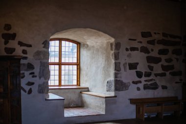 Antika mobilyalarla, taş duvarlarla ve sıcak ışıkla dolu eski bir şato. Tarih ve gizemle dolu bir ortaçağ atmosferi yaratıyor..