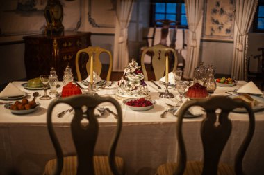 Ahşap bir masanın üzerinde ortaçağ yemekleri sergilenen eski bir şato mutfağı. Tarihi atmosfer, miras sergisi için antika dekorlar, çömlekçilik ve sahte yiyeceklerle yeniden canlandırıldı..