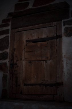 Ortaçağ şatosunun içindeki ahşap bir kapıya antik kapı kolları ve kilitleri yakın çekimde, eski dokulara sahip ayrıntılı metal işçiliği ve tarihi işçiliği gösteriyor..