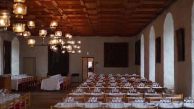 Uzun ahşap masalar, avizeler, taş duvarlar ve sıcak mum ışığı olan bir ortaçağ şatosu ziyafeti salonu. Kraliyet ziyafetlerinin görkemli tarihi atmosferi, 4K ultra HD ile yakalandı..