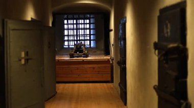 Ortaçağ şatosunun içindeki karanlık taş hapishane paslı parmaklıklar, zincirler ve soğuk duvarları aydınlatan meşale ışığı. 4K ultra HD ile yakalanan tarihi mimari ve eski mahkumiyetin atmosferi.