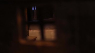 Ortaçağ şatosunun içindeki karanlık taş hapishane paslı parmaklıklar, zincirler ve soğuk duvarları aydınlatan meşale ışığı. 4K ultra HD ile yakalanan tarihi mimari ve eski mahkumiyetin atmosferi.