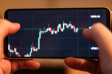 Şifreleme ile ilgili metin ya da ekranda numaralar olan bir cep telefonunu tutan ellerin yüksek kaliteli fotoğrafı. Teknoloji fotoğrafçılığı, fintech kavramları, kripto piyasası makaleleri, finansal uygulamalar ve dijital para birimi temaları için mükemmel..