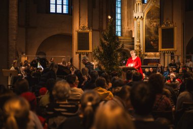 Finlandiya. 21.12.2025. Bir kilisenin içinde şarkıcıların neşeli şarkılar söylediği bir Noel ve Yeni Yıl konserinin fotoğrafı. Görüntü, kilisenin iç dekorasyonunu, icracılarını ve dini temalar için ideal sıcak tatil atmosferini yakalıyor.