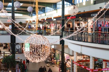 Finlandiya. Aralık 2025. Noel ve yeni yıla hazırlanan insanlarla dolu büyük bir alışveriş merkezinin fotoğrafı. Müşteriler dekore edilmiş alışveriş merkezlerinin iç kısımlarında yürürler, çanta taşırlar ve festival atmosferinin tadını çıkarırlar.