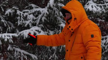 Adamın eli kar yağarken çam ağacından kar sallıyor. 4K video