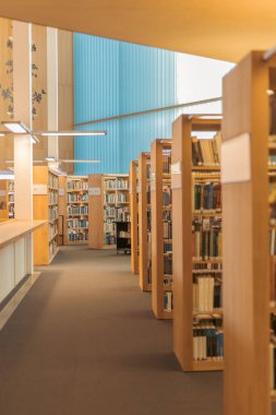 Sıralar dolusu kitap rafları kütüphane koridorunda sıcak ve davetkar bir atmosfer yaratıyor. Arka plan hafifçe bulanık ve bulanık....