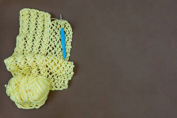 Kahverengi arka planda el yapımı tığ işi kumaşlı iplik topu ve örgü kancası, kopya alanı olan hobi ve el işi.
