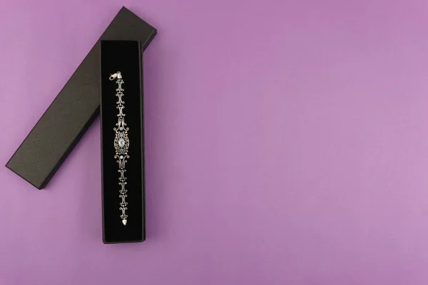 Süslü dekoratif tasarım içeren birinci sınıf gümüş bilezik siyah lüks hediye kutusunda sunuluyor. Temiz eflatun arkaplan tanıtım metni ya da markalaşma için mükemmel bir kopya alanı sağlar. Mücevher reklamı ve hediye için ideal. 