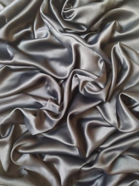 Güzel akışkan perdeleri ve zarif kıvrımları olan kaliteli gümüş ipek kumaş lüks doku arkaplanı oluşturur. Pürüzsüz saten kumaş parlak ve yumuşak dalgalar, moda, tekstil endüstrisi, lüks markalaşma ve zarif tasarım için mükemmel.