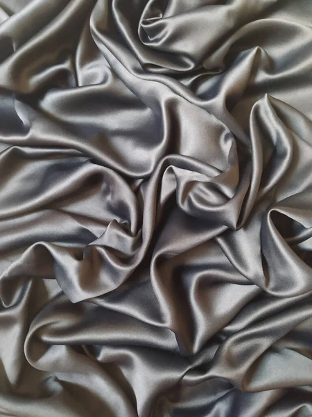 Güzel akışkan perdeleri ve zarif kıvrımları olan kaliteli gümüş ipek kumaş lüks doku arkaplanı oluşturur. Pürüzsüz saten kumaş parlak ve yumuşak dalgalar, moda, tekstil endüstrisi, lüks markalaşma ve zarif tasarım için mükemmel.