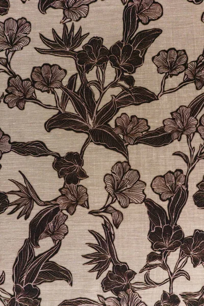 Tarafsız bej kumaş dokusunun detaylı bir yakın çekimi. Büyük bir tropikal çiçek deseni ve koyu kahverengi yapraklar. Klasik ve modern tasarım projeleri için