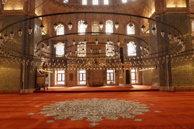 İstanbul Eminonu 'da Yeni Cami Camii' nin büyük dairesel avizeleri, kırmızı halısı ve vitray pencereleri olan güzel bir iç mekanı.