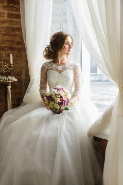 Güzel bir odada, beyaz bir elbise içinde bir buketle gelin.