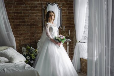 Güzel bir odada, beyaz bir elbise içinde bir buketle gelin.