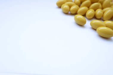 Beyaz arka planda sarı yumuşak kapsüller, vitamin takviyeleri