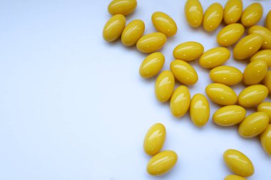 Beyaz arka planda sarı yumuşak kapsüller, vitamin takviyeleri
