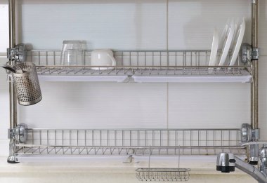 Lavabonun üzerinde tabaklar, bardaklar ve mutfak aletleriyle duvarlara monte edilmiş kurutma askısı.