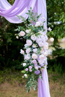 Çiçekler ve kumaşla süslenmiş romantik açık hava düğün kemeri.