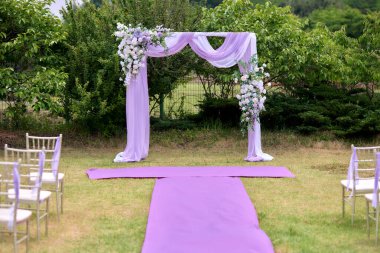 Çiçekler ve kumaşla süslenmiş romantik açık hava düğün kemeri.