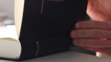 İncil 'i açıp evde dua eden genç bir kadın. Doğal ışıkta sakin, samimi ve otantik bir an. İnanç kavramı, maneviyat, umut, yansıma ve iç huzur.