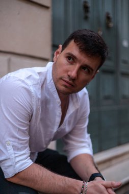 İtalya, Roma 'da taştan bir bankta oturan beyaz gömlekli ve siyah pantolonlu bir adamın portresi..