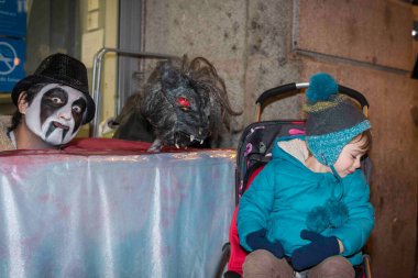 Küçük çocuk arabasında annesiyle yürüyor ve Noel şenlikleri boyunca sokak oyunlarından zevk alıyor..