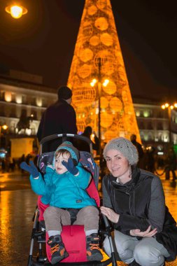 Anne, İspanya, Madrid 'de Noel tatilinde, soğuk bir gecede küçük çocuğuna ışık dekorasyonunu gösteriyor.