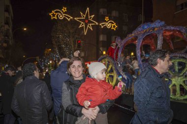 Anne ve küçük çocuğu Madrid, İspanya 'daki Üç Kral Geçit Töreni' nde, soğuk ve yağmurlu bir gecede.