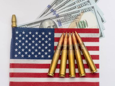 100 dolarlık banknotlarla küçük bir Amerikan bayrağına yerleştirilmiş birkaç tüfek mermisi gücü, finansmanı ve çatışmayı simgeliyor..