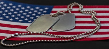 Amerika Birleşik Devletleri 'nde vatanseverliği, fedakarlığı ve askerlik onurunu temsil eden bir Amerikan bayrağının üzerinde duran gümüş künyelere yakın durun..