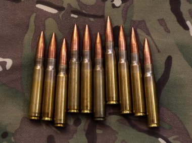 Askeri kamuflaj tekstiline yerleştirilmiş çoklu tüfek fişeklerine yakından bakın. Savaşı, savunmayı, mühimmatı ve silahlı kuvvetleri sembolize ediyor..
