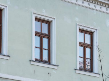Açık yeşil alçı ve ahşap pencere çerçeveleriyle klasik mimari tarzında tarihi bir binanın ön cephesi.