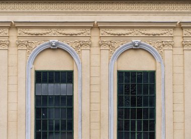 Klasik mimari tarzında kemerli pencereleri ve dekoratif kaplaması olan tarihi bir binanın cephesi..