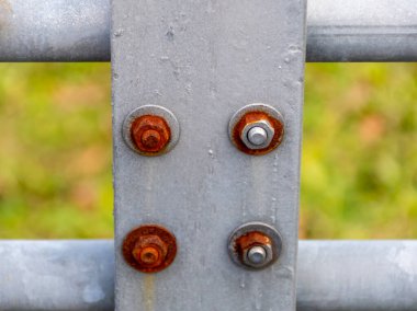 Çit yapısındaki paslı ve temiz metal cıvatalar tasarımın teknik endüstriyel dokusu olarak kullanılıyor..