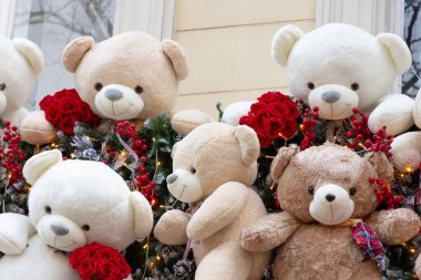 Çiçekli ve Noel süslemeli oyuncak ayılar, şehir vitrininde.