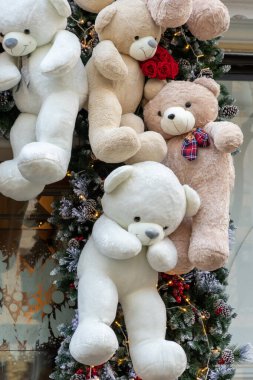 Çiçekler ve Noel ağacı süslemeleri ile bir Noel enstalasyonunda farklı renkte peluş ayılar.