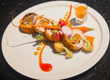 Elegant gourmet chicken roulade stuffed with fresh spinach, carrots, and peppers, beautifully plated with roasted vegetables and vibrant sauce drops.