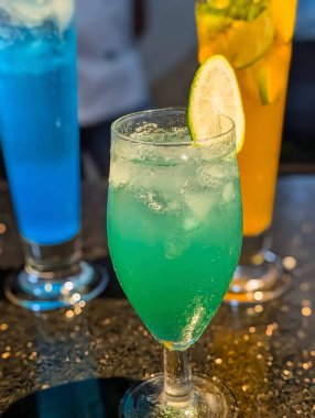 Chilled tropical mocktail served in a glass with lime slice and ice cubes. Refreshing summer beverage with vibrant blue and green tones, perfect for bar, cafe, or restaurant presentation.
