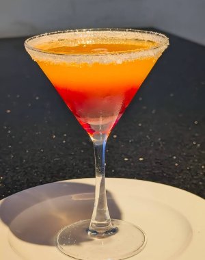 Vibrant two-tone sunset mocktail served in a martini glass with a sugared rim. The refreshing orange and red layers create a beautiful gradient effect, perfect for summer drink menus.
