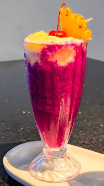 Colorful dragon fruit and pineapple smoothie served in elegant glasses, topped with creamy froth and garnished with fresh fruit and a cherry.