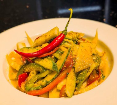 Colorful mixed mango salad with sliced mango, cucumber, chili, and herbs, seasoned with tangy spices and garnished with a fresh green chili.