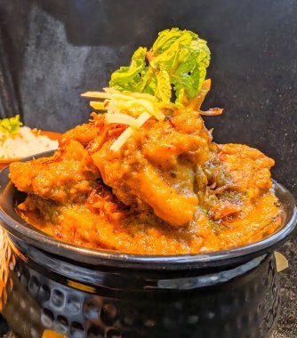 Authentic Indian chicken curry in a traditional brass kadai,garnished with fresh ginger and mint leaves.Rich, aromatic, and flavorful curry with thick gravy, perfect for depicting Asian cuisine.