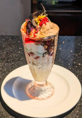Delicious chocolate sundae served in a tall glass with layers of ice cream, chocolate syrup, nuts, and cherry topping.