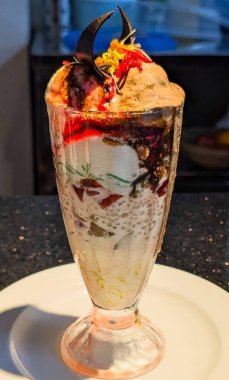 Delicious chocolate sundae served in a tall glass with layers of ice cream, chocolate syrup, nuts, and cherry topping.