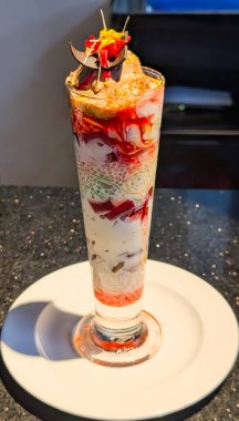 Delicious chocolate sundae served in a tall glass with layers of ice cream, chocolate syrup, nuts, and cherry topping.